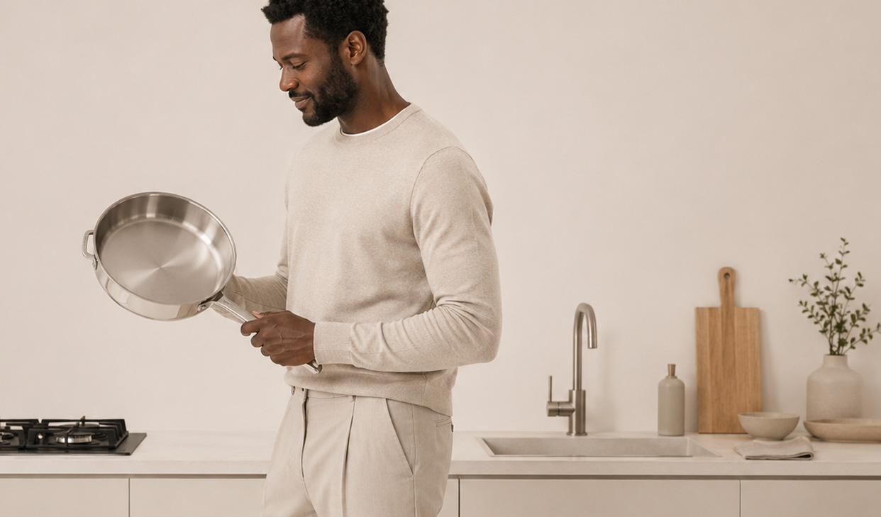 Homem segurando uma panela elegante em uma cozinha clara
