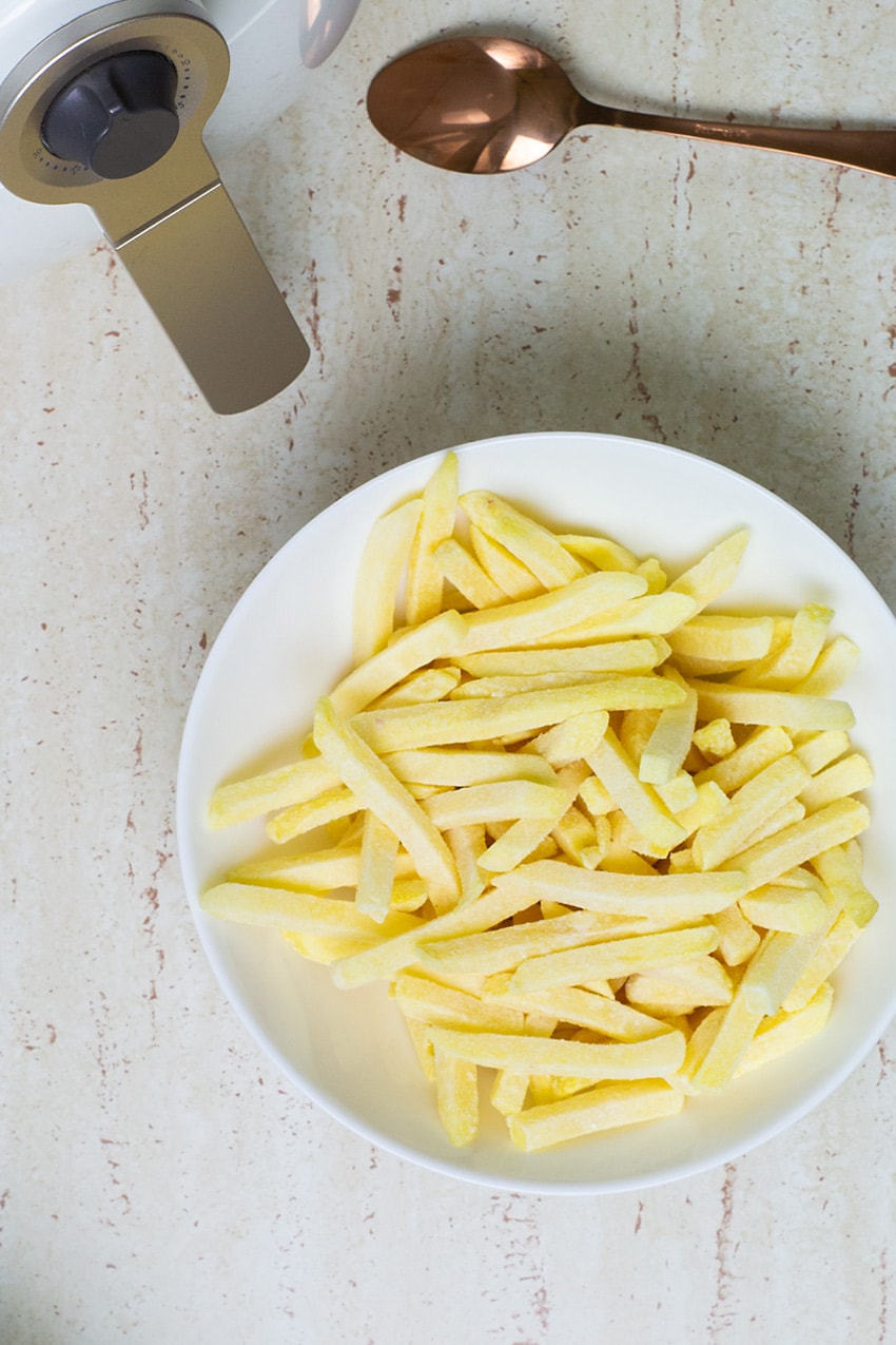 batatas palito sendo temperada para ser levada à fritadeira airfryer